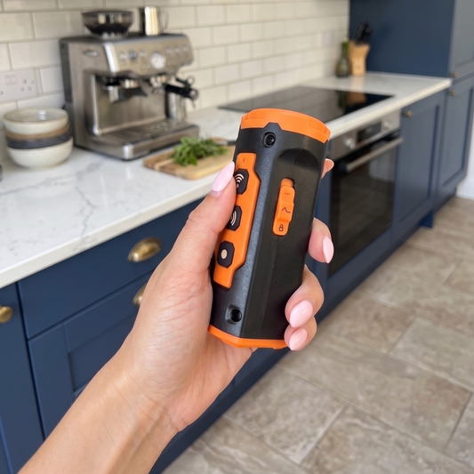 Hand holding a dog training device in a kitchen setting