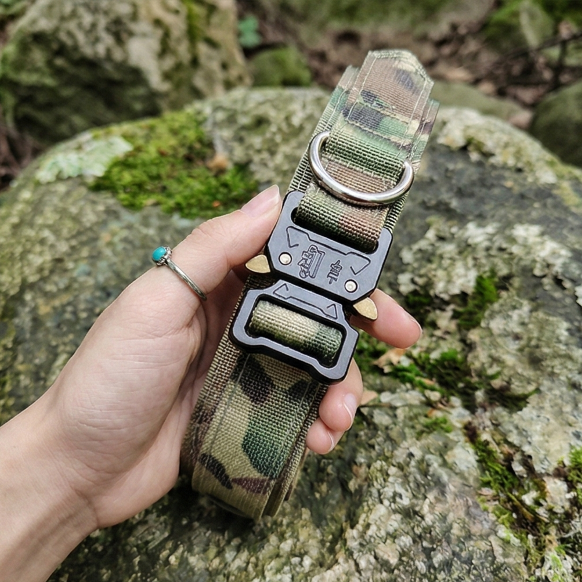 Camouflage dog collar with metal buckle held by a hand against a natural background