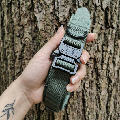 Green tactical belt with a black buckle held by a hand against a tree bark background
